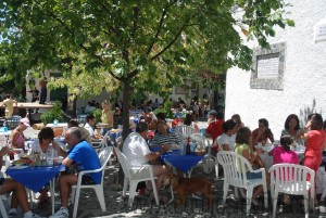 People enjoying drinks tapas and food outside in the main square Pampaneira